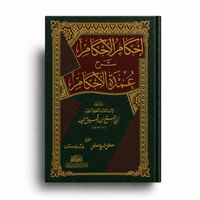 Livre arabe relié à couverture verte et bordeaux avec dorures, intitulé « Ihkâm al-Ahkâm Charh ‘Umdat al-Ahkâm », présenté de face sur fond blanc avec ombre portée.