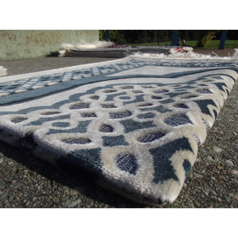 Tapis de prière Sana Edition avec contour géométrique bleu ardoise sur fond blanc, motif élégant et traditionnel.