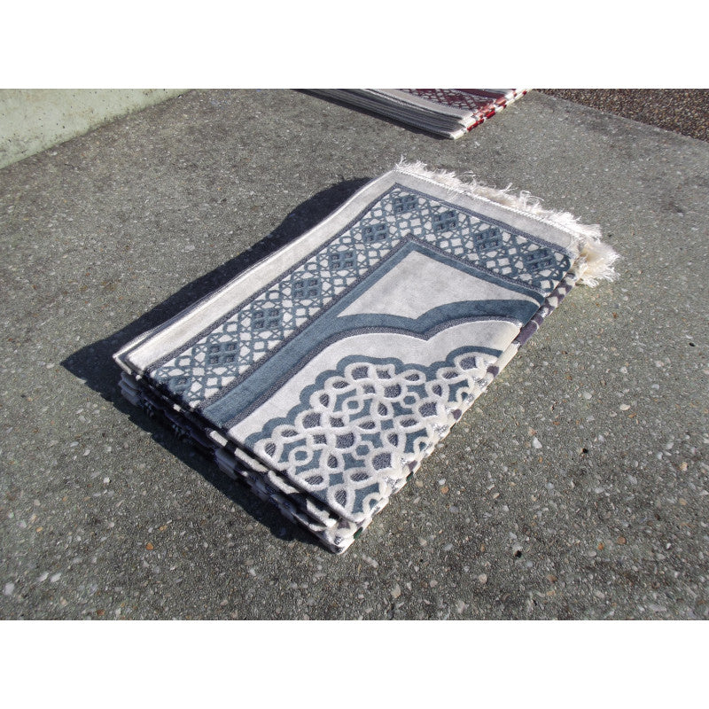 Tapis de prière Sana Edition avec motif géométrique bleu ardoise sur fond blanc, vue de face.