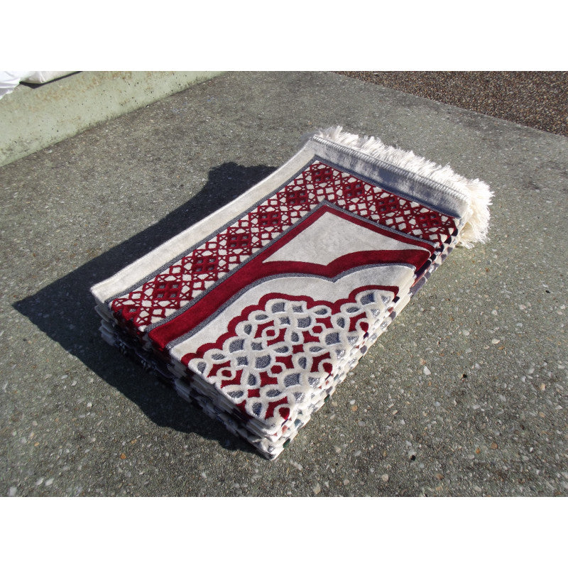 Tapis de prière Sana Edition avec motif géométrique rouge sur fond blanc, vue de face, détaillé et coloré.