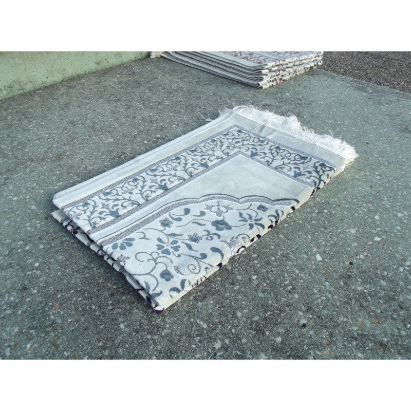 Tapis de prière Sana Edition avec motif jardin, fond blanc et couleur bleu ardoise, illustrant un design élégant et apaisant.
