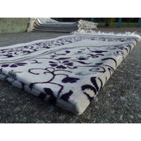 Tapis de prière Sana Edition avec motif jardin, fond blanc et couleur violet, visible en détail dans l'image.