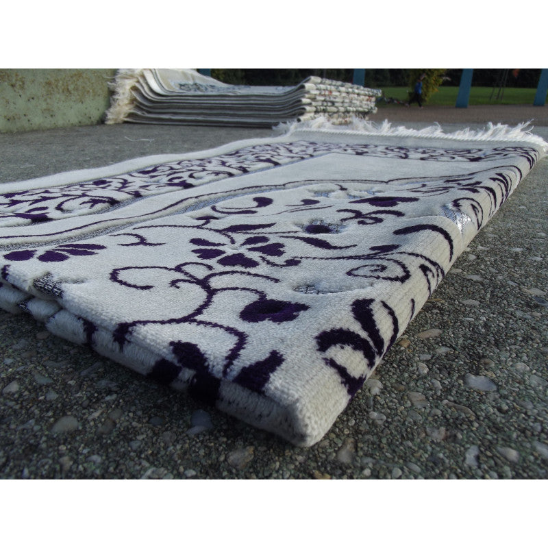 Tapis de prière Sana Edition avec motif jardin, fond blanc et couleur violet, visible en détail dans l'image.